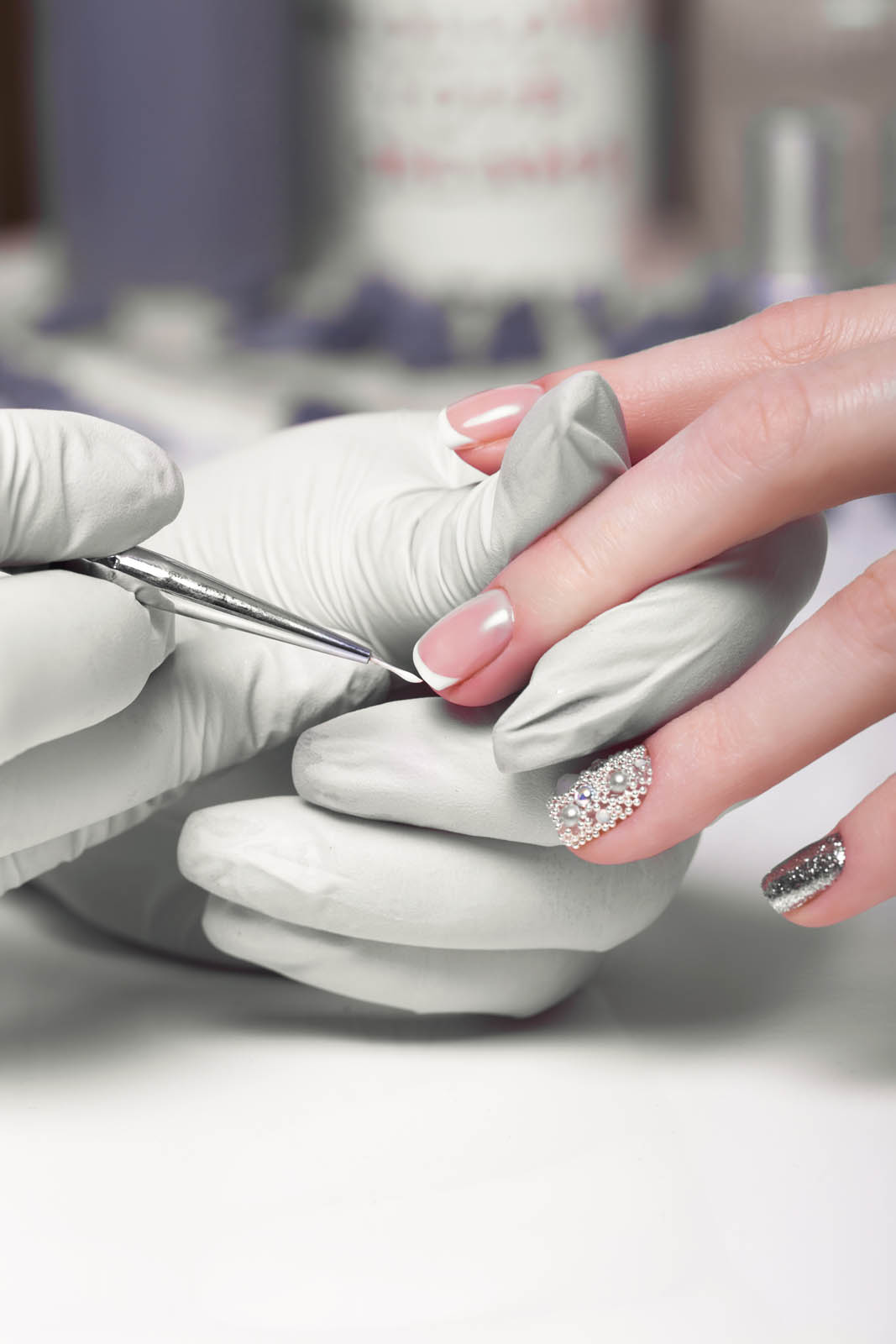 Closeup finger nail care by manicure specialist in beauty salon. Manicurist paints nails with nail polish